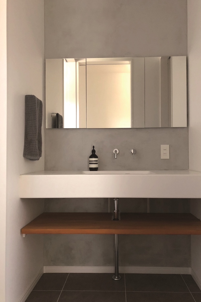 大きめの鏡台が置かれた洗面台。収納部分を木材にすることでカラーアクセントに