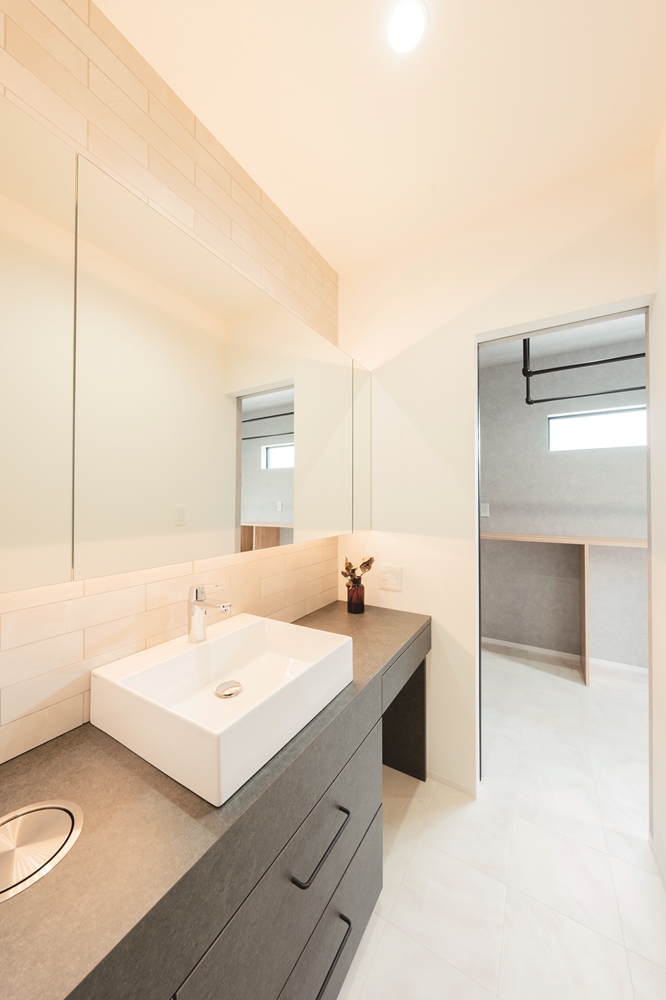 広々とした洗面台は、壁一面が鏡になっているホテルライクな仕様。カウンターと棚は、M邸のイメージに合わせた色合いで造作している